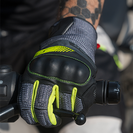 detalle empuñando el grip con guantes de cuero color neon puestos