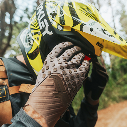 poniendose los goggles con guantes de enduro y motocross en color cafe