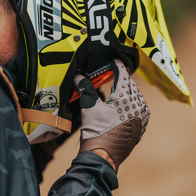 piloto de carreras con guantes de enduro y motocross en color cafe