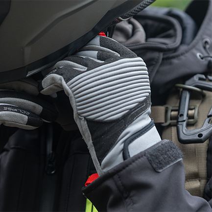 Piloto poniendose el casco de la moto con Guantes de proteccion grises