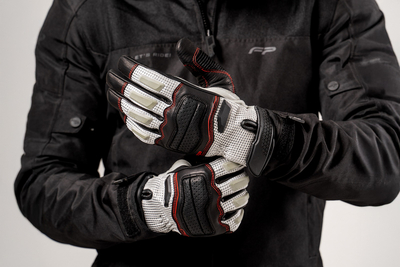 Motociclista ajustando guantes de cuero Asphalt Gris con malla ventilada y refuerzo en nudillos, ideales para conducción urbana y touring.