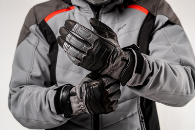 Motociclista ajustando guantes de cuero Asphalt Negro con malla ventilada y protecciones rígidas, ideales para ciudad y touring