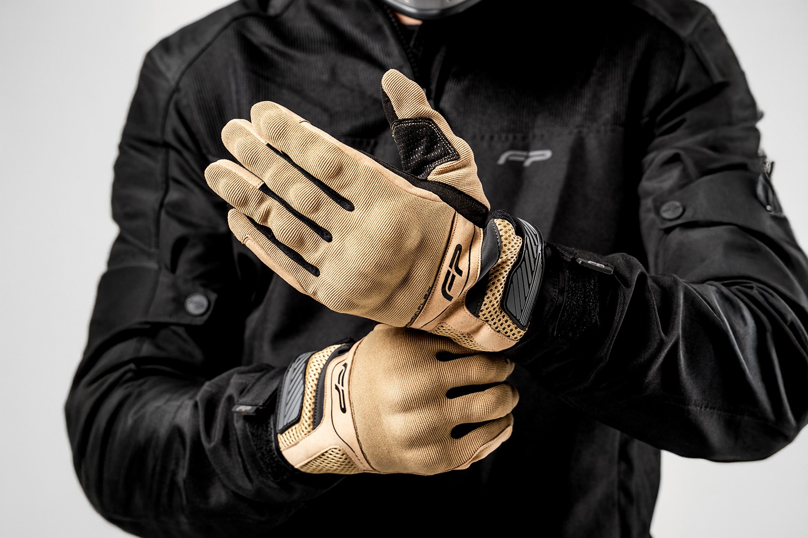 Motociclista ajustando guantes Core color arena, flexibles y ventilados para uso diario en moto