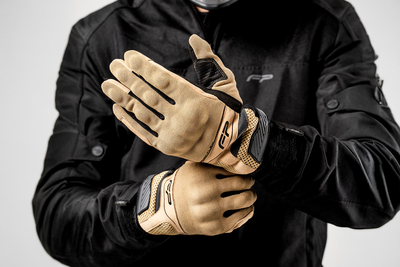 Motociclista ajustando guantes Core color arena, flexibles y ventilados para uso diario en moto