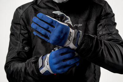 Motociclista ajustando guantes Core azul navy ventilados para moto, diseño ergonómico y seguro