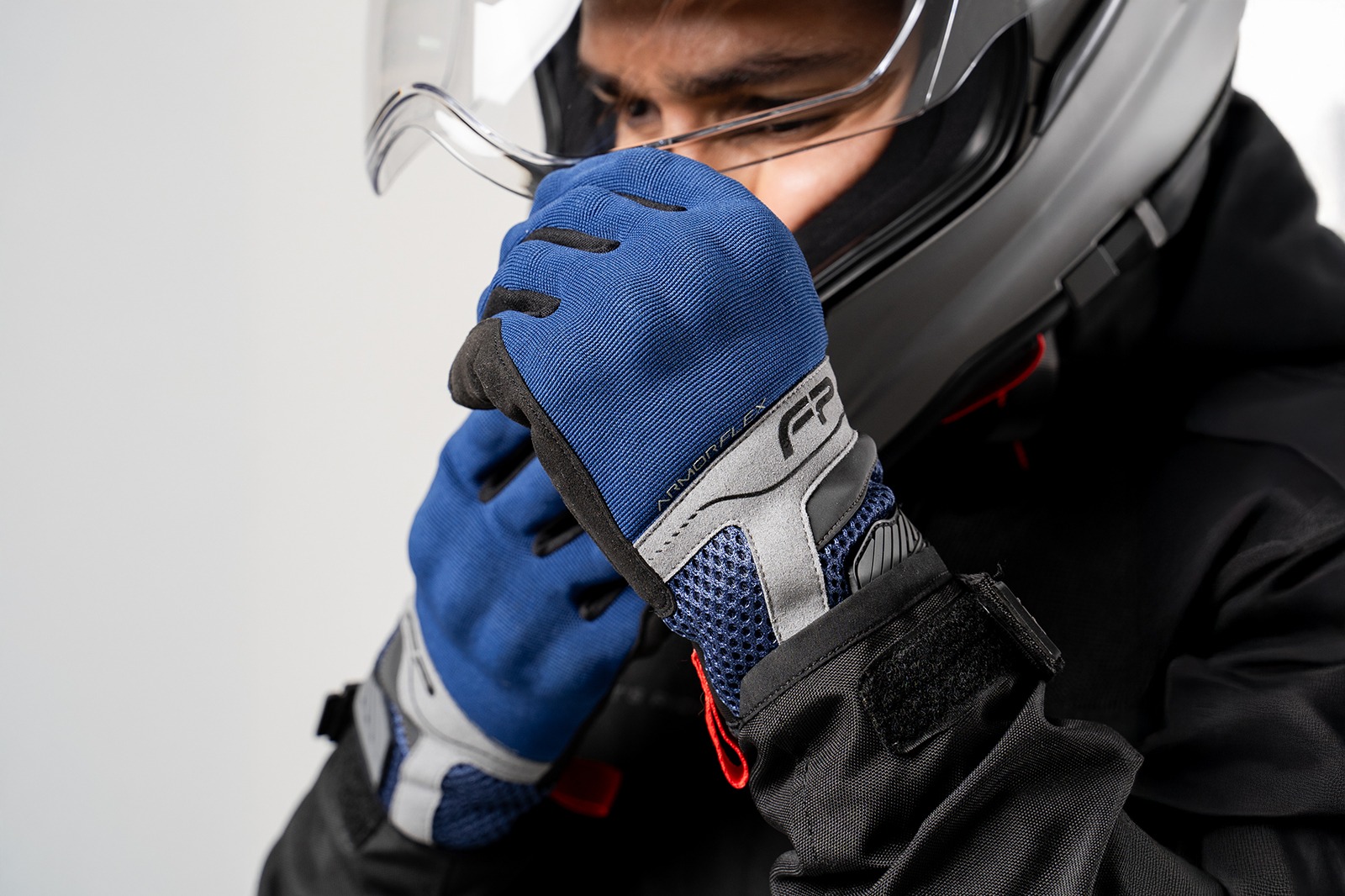 Motociclista con casco colocándose guantes Core azul navy ventilados, ideales para climas cálidos y conducción urbana