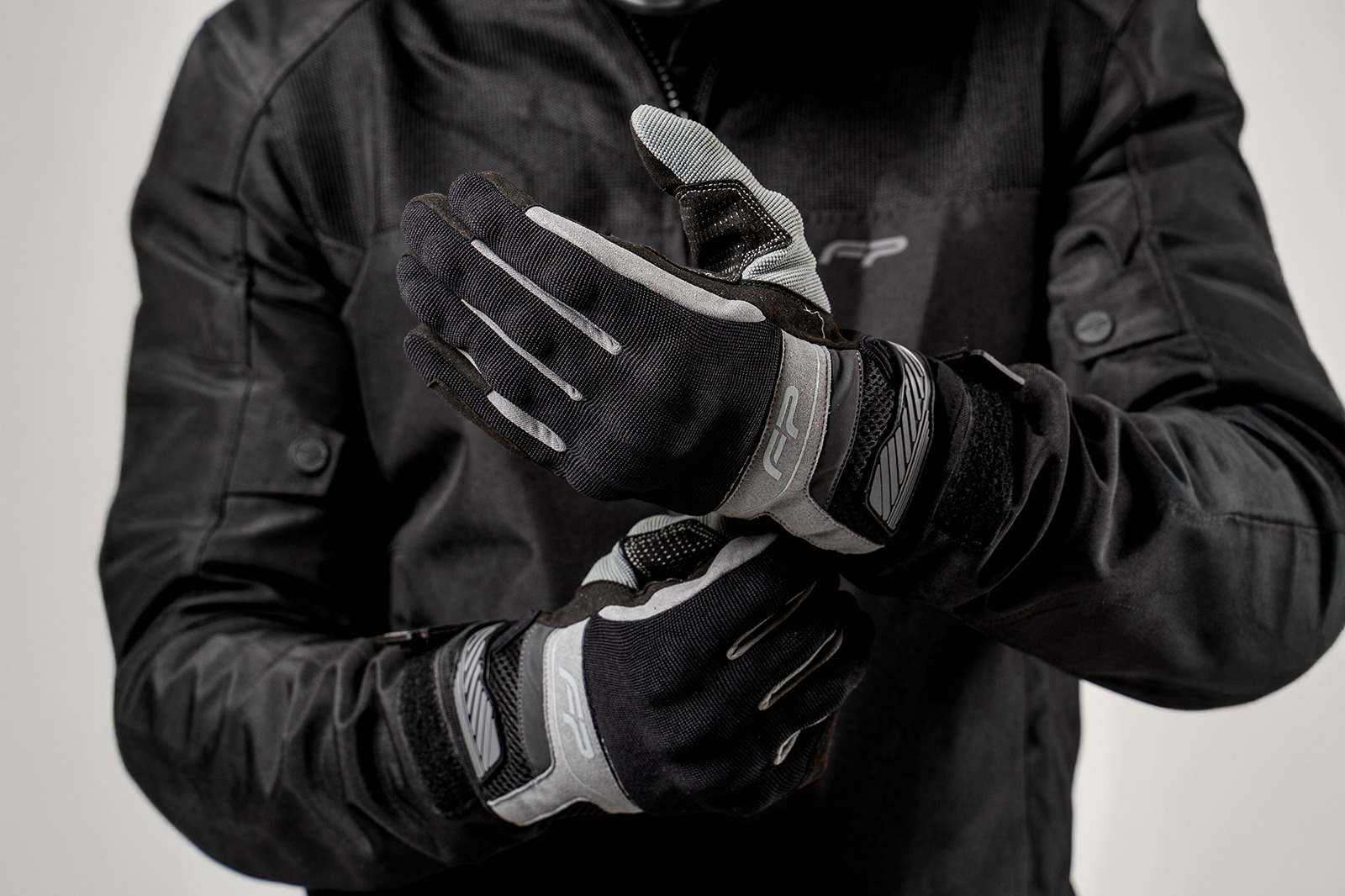 Motociclista ajustando guantes Core grises ventilados para moto, diseño ergonómico y cómodo