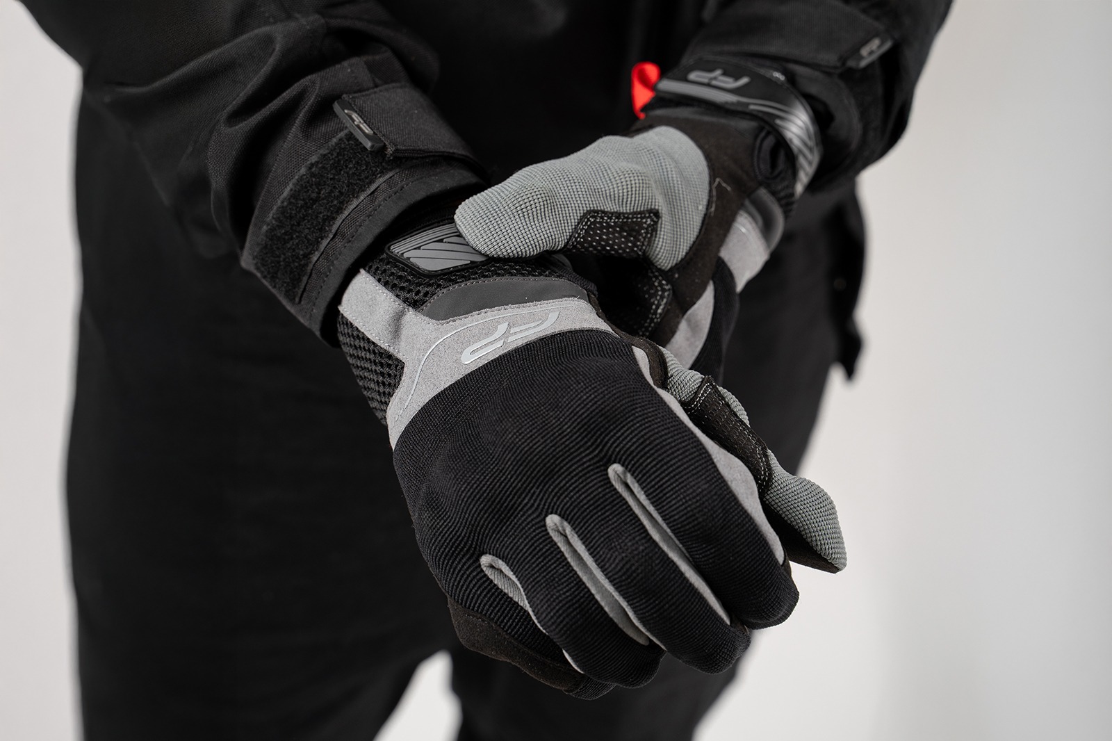 Motociclista colocándose guantes Core grises ventilados, ideales para climas cálidos y conducción urbana