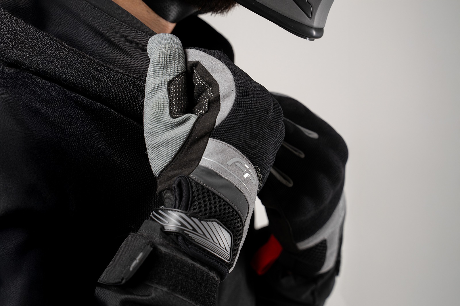 Motociclista con casco usando guantes Core grises ventilados, protección y estilo para viaje en moto