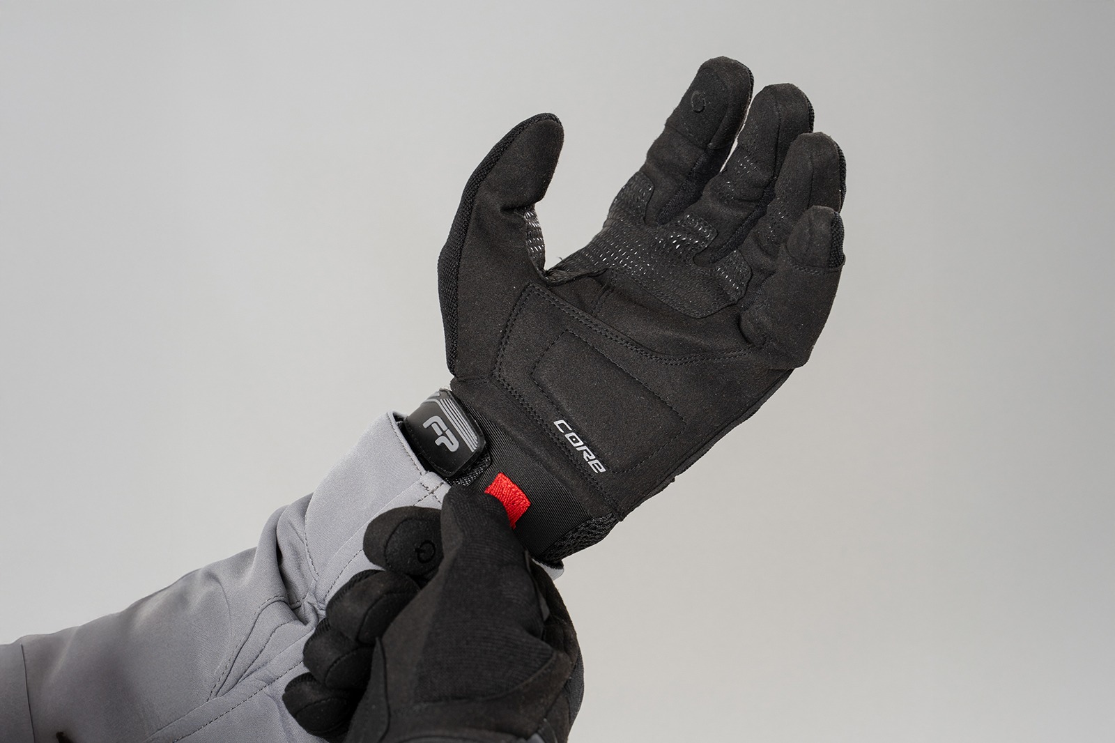 Motociclista colocándose guantes Core negros ventilados, ideales para conducción en clima cálido