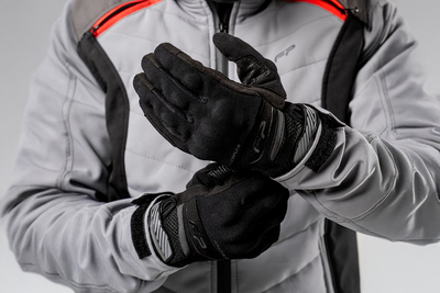 Motociclista ajustando guantes Core negros ventilados para moto, diseño ergonómico y seguro