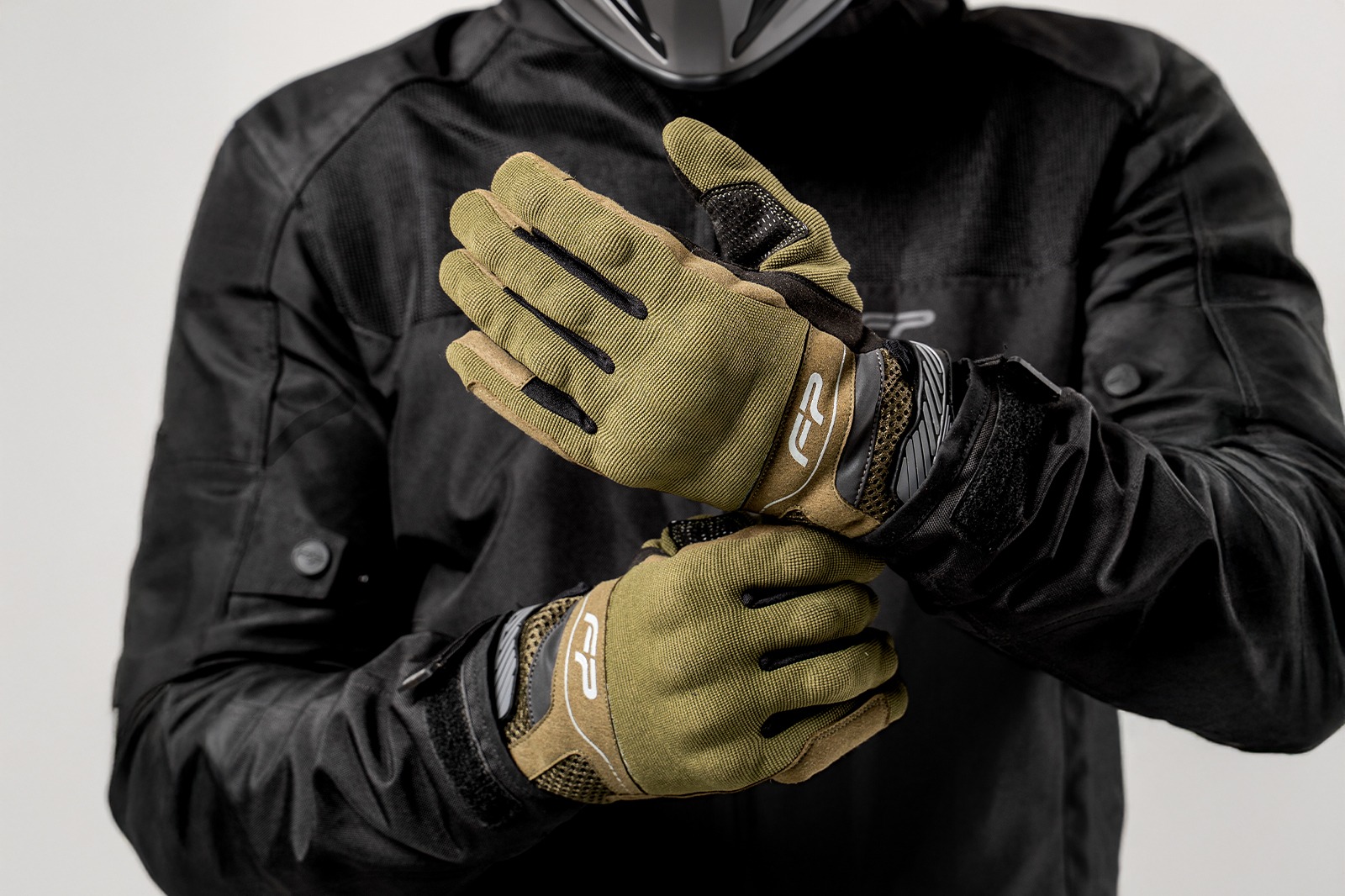 Motociclista ajustando guantes Core verde militar ventilados para moto, diseño ergonómico y seguro