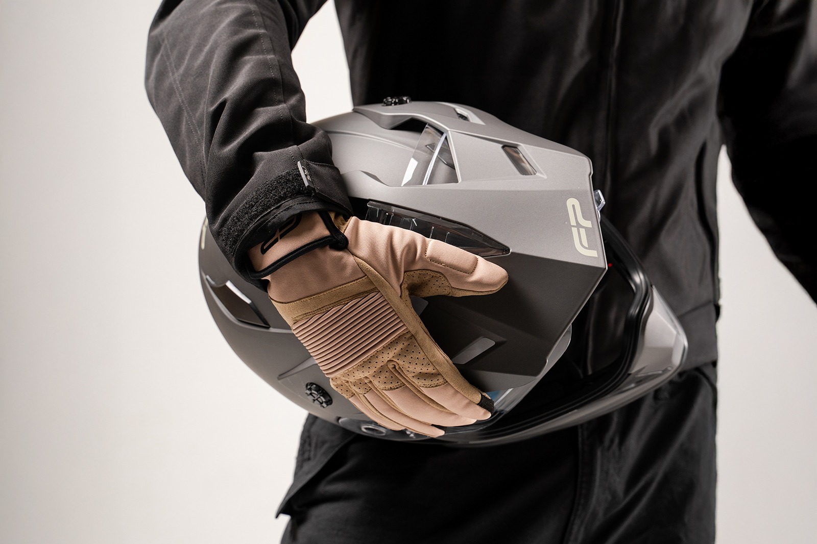 Piloto sosteniendo el casco con guantes de protecciones para moto clasicos de color café