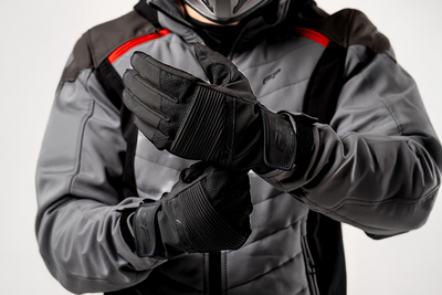 Motociclista ajustando guantes deportivos Eclipse Negro con cierre de velcro y diseño urbano para uso diario