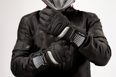 Motociclista ajustando guantes impermeables Maverick Negro con membrana Hipora® y diseño ergonómico para turismo en moto