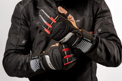 Motociclista ajustando guantes impermeables Maverick Tobacco con membrana Hipora® y diseño clásico para turismo en moto