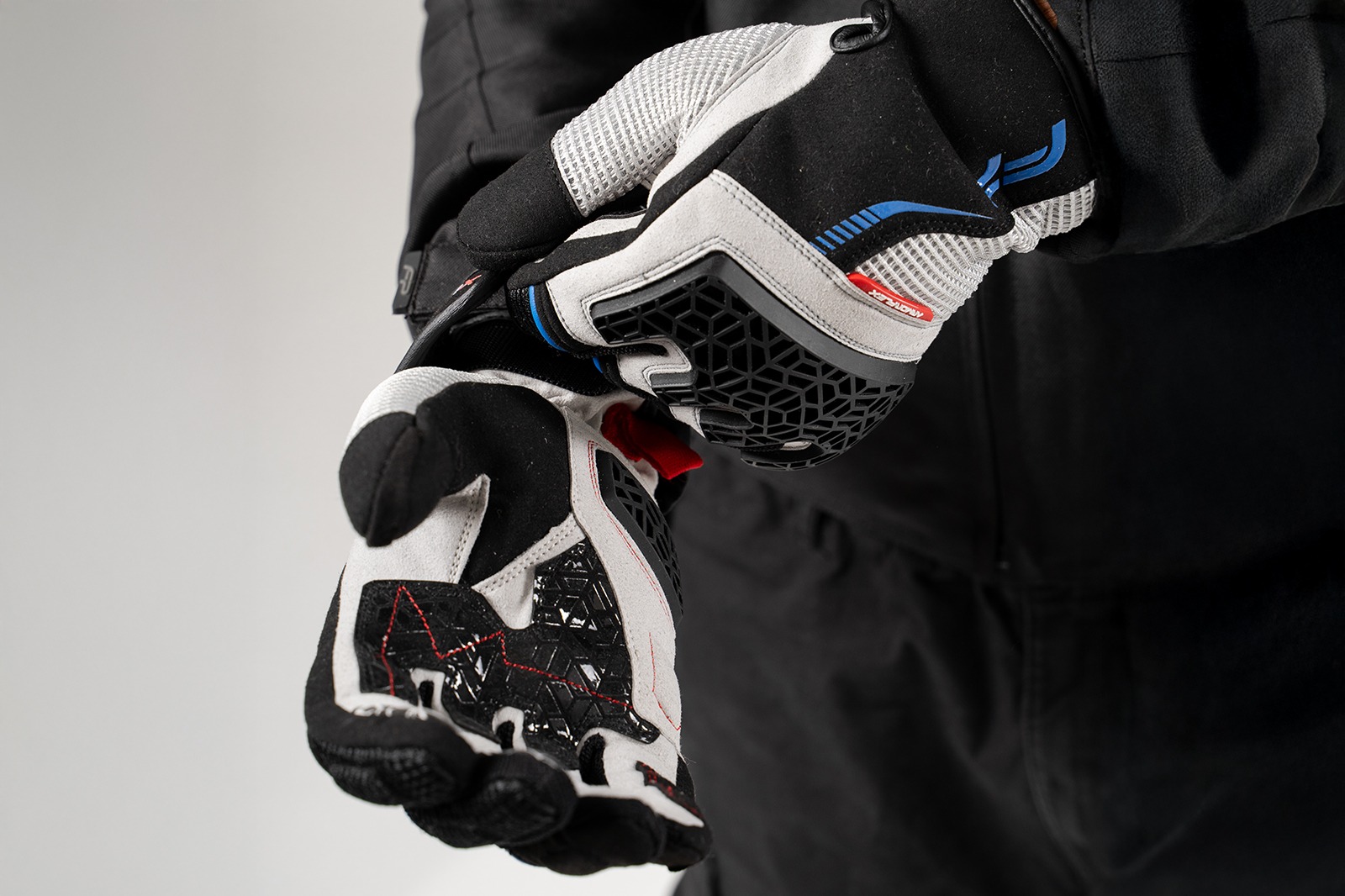 Motociclista mostrando palma reforzada de guantes Xplorer gris con material Chamude y silicona