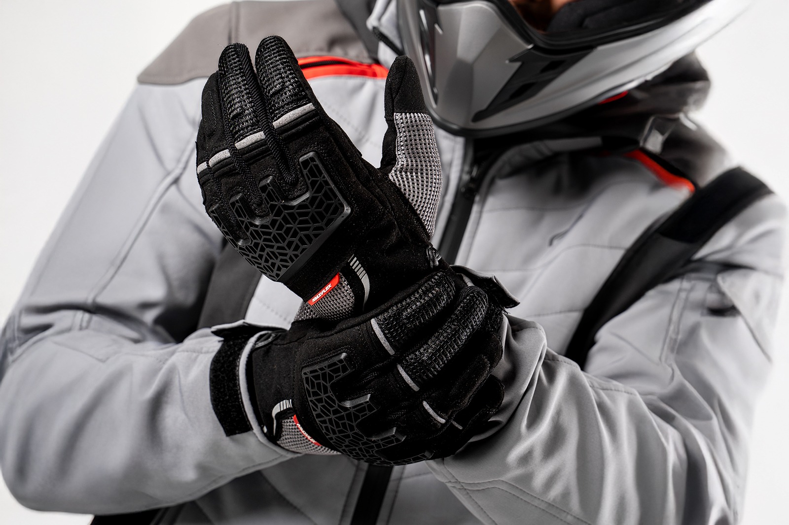Motociclista con casco usando guantes Xplorer negros para moto, ideales para turismo y aventura