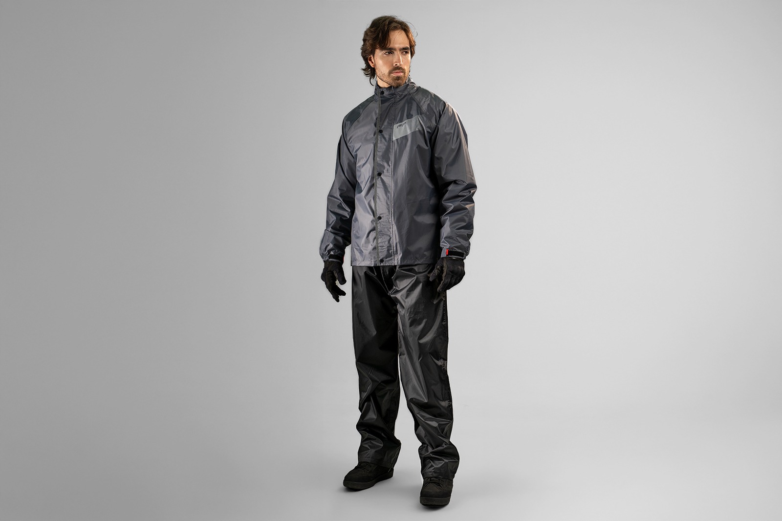 Impermeable para moto Storm color negro y rojo completo
Detalle de botones del cierre frontal impermeable Storm
Chaqueta impermeable gris Storm sobre piloto urbano
Ajuste en pu&ntilde;os con velcro del impermeable Storm
Pantal&oacute;n negro del Storm con botones e
