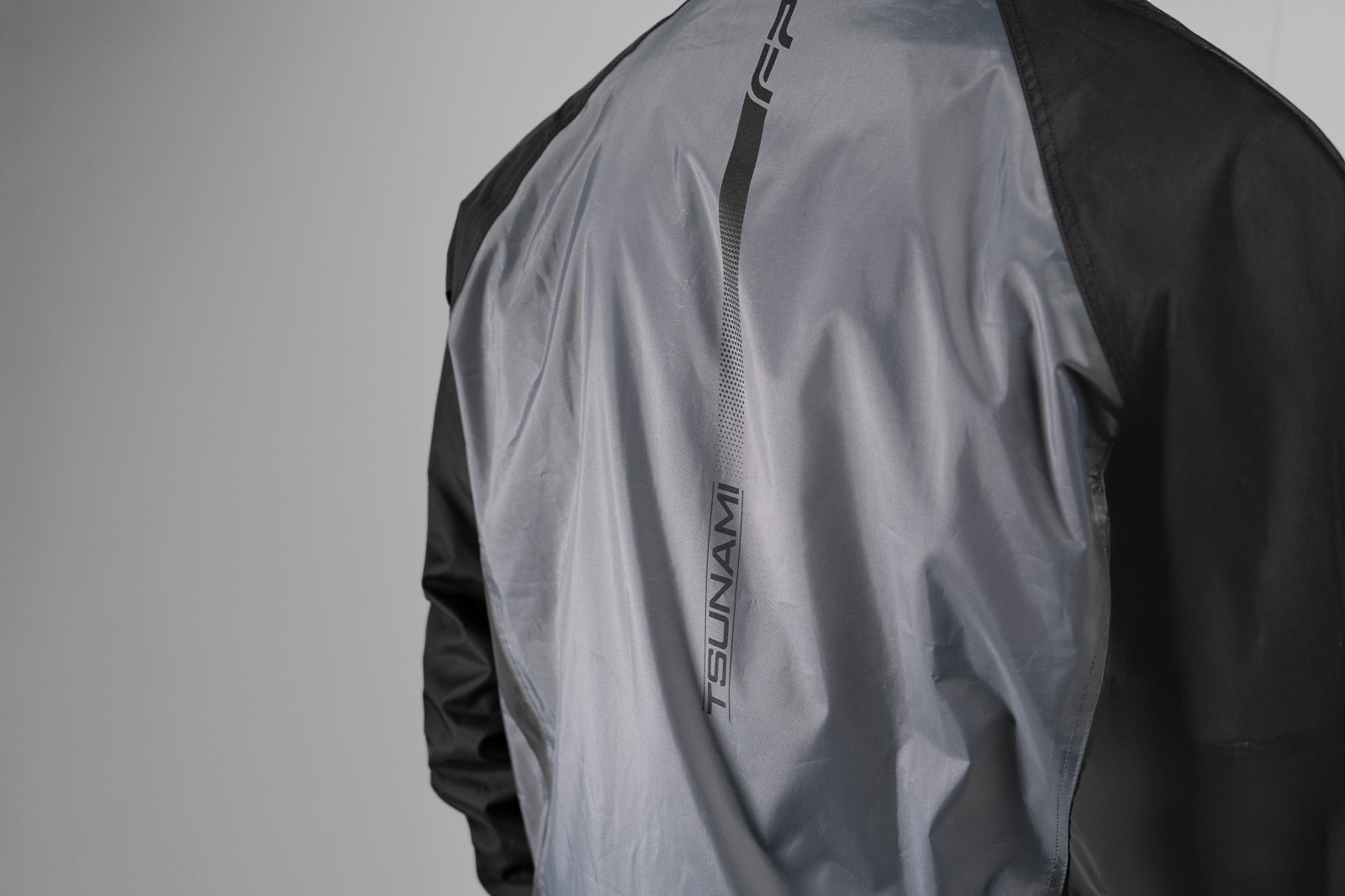 Vista trasera del impermeable negro con reflectivos y logo Tsunami