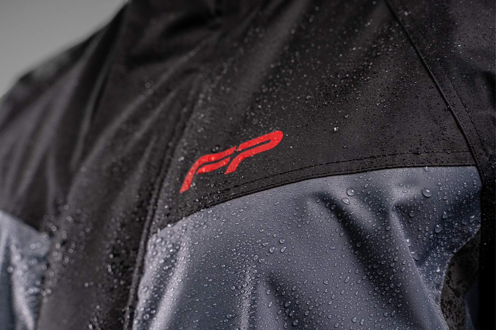 Cierre frontal del impermeable FP negro con doble solapa y velcro