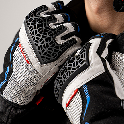 Guantes Xplorer gris de FP Moto, diseño moderno y resistente para pilotos de aventura Guantes Xplorer gris para moto con diseño robusto y detalles azules, puestos en manos de motociclista