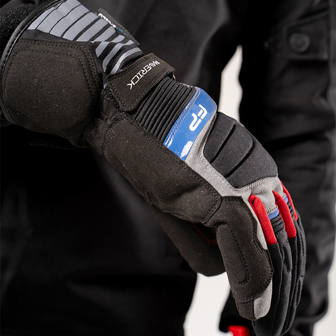 Guante Maverick Gris impermeable con detalles en azul y rojo, combina visibilidad, estilo y protección.