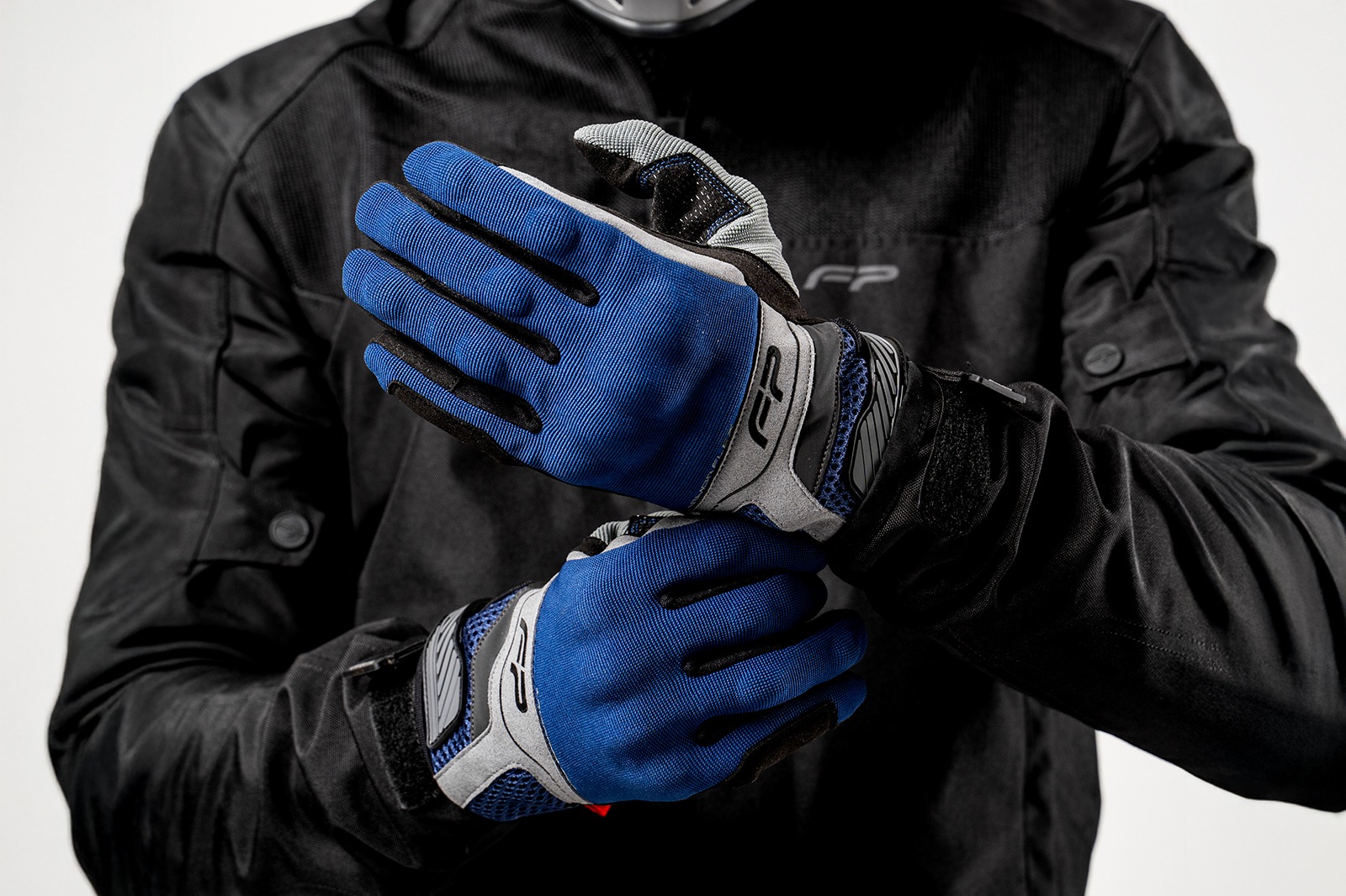 Motociclista ajustando guantes Core azul navy ventilados para moto, diseño ergonómico y seguro