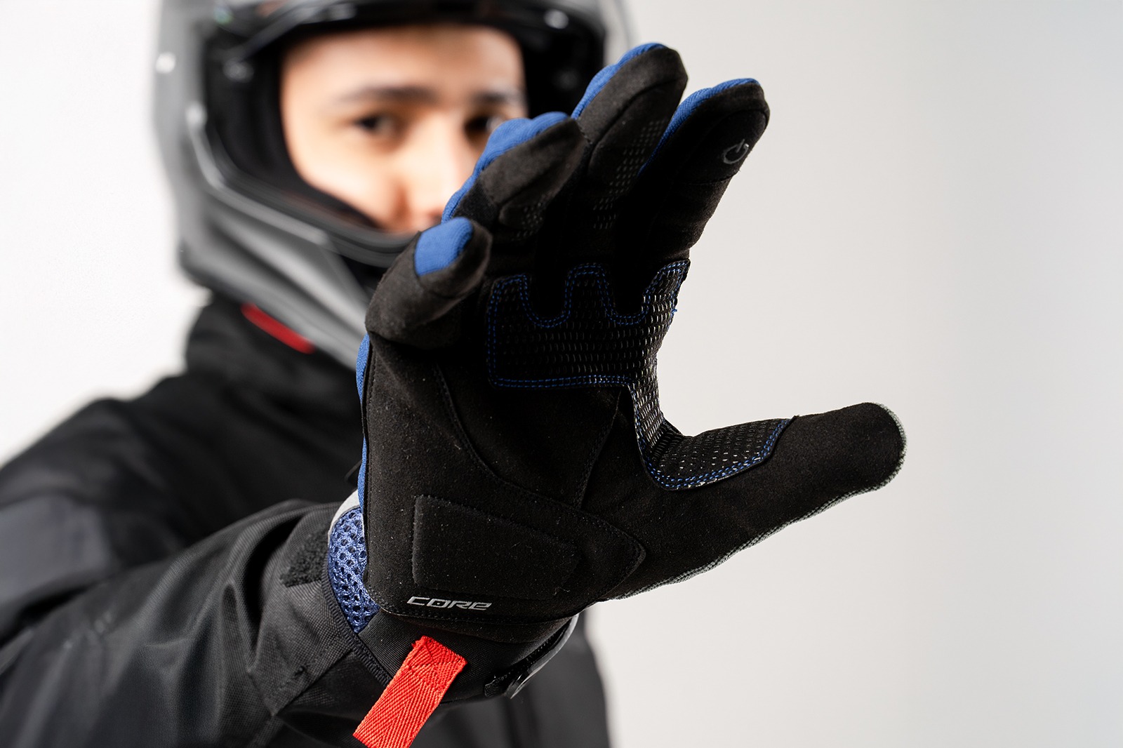 Motociclista mostrando palma de guantes Core azul navy ventilados, agarre firme y protección para viajes en moto