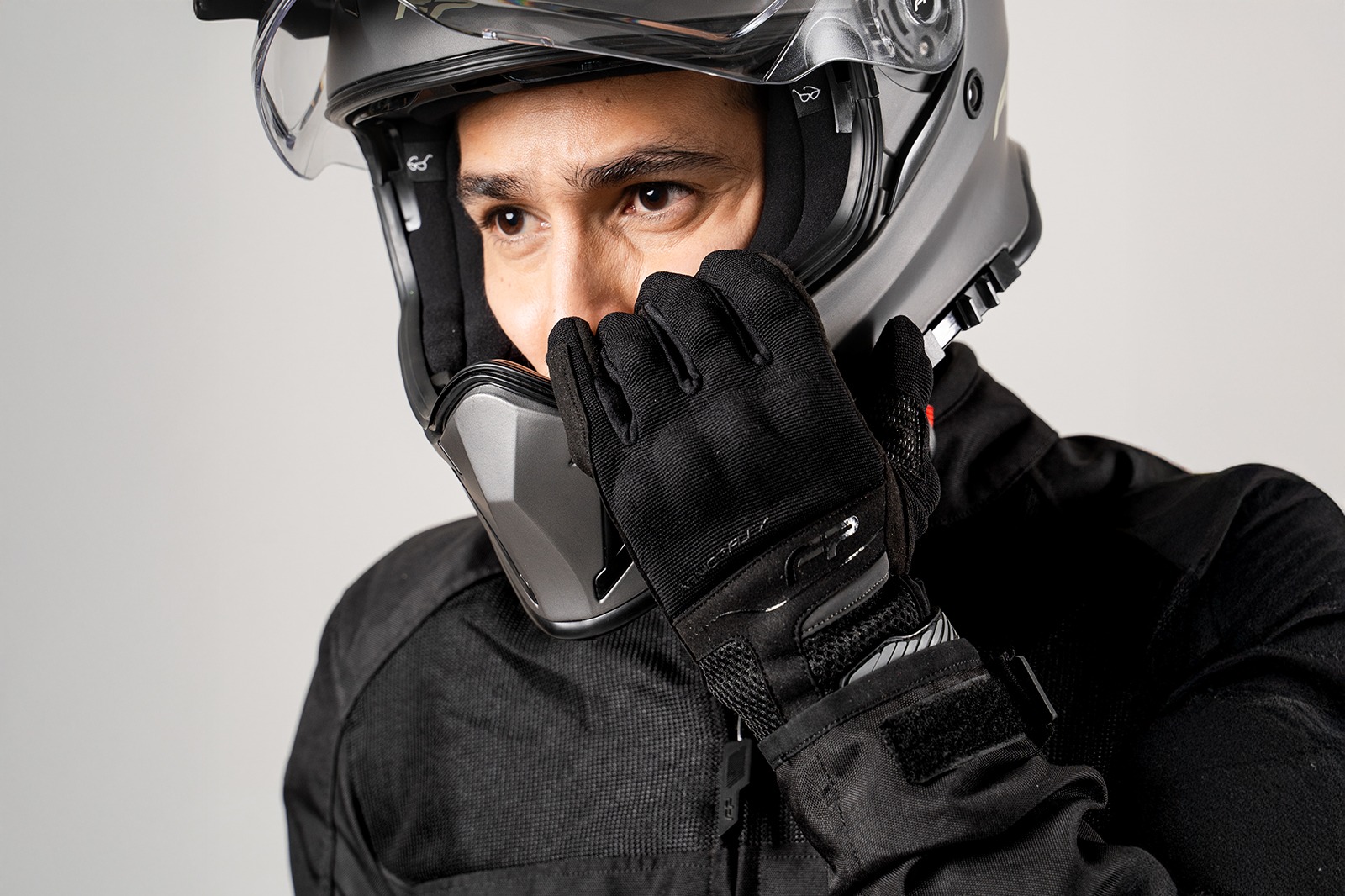 Motociclista con casco usando guantes Core negros ventilados, protección y comodidad en carretera