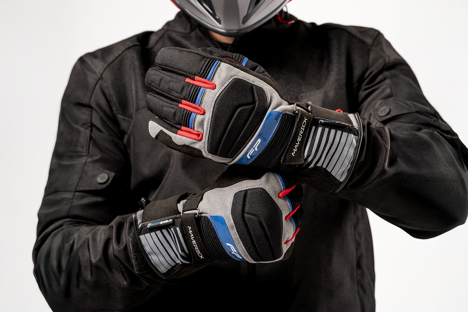 Motociclista ajustando guantes impermeables Maverick Gris con membrana Hipora y protecciones para turismo en moto.
