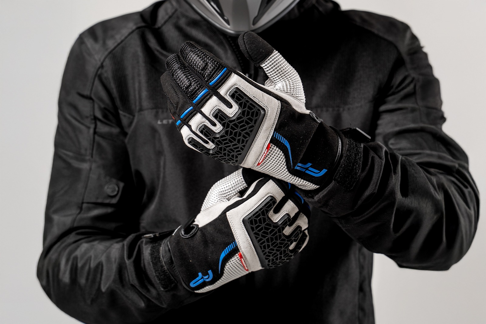 Motociclista usando guantes Xplorer gris para moto, vista frontal cruzada con detalles azules y negros